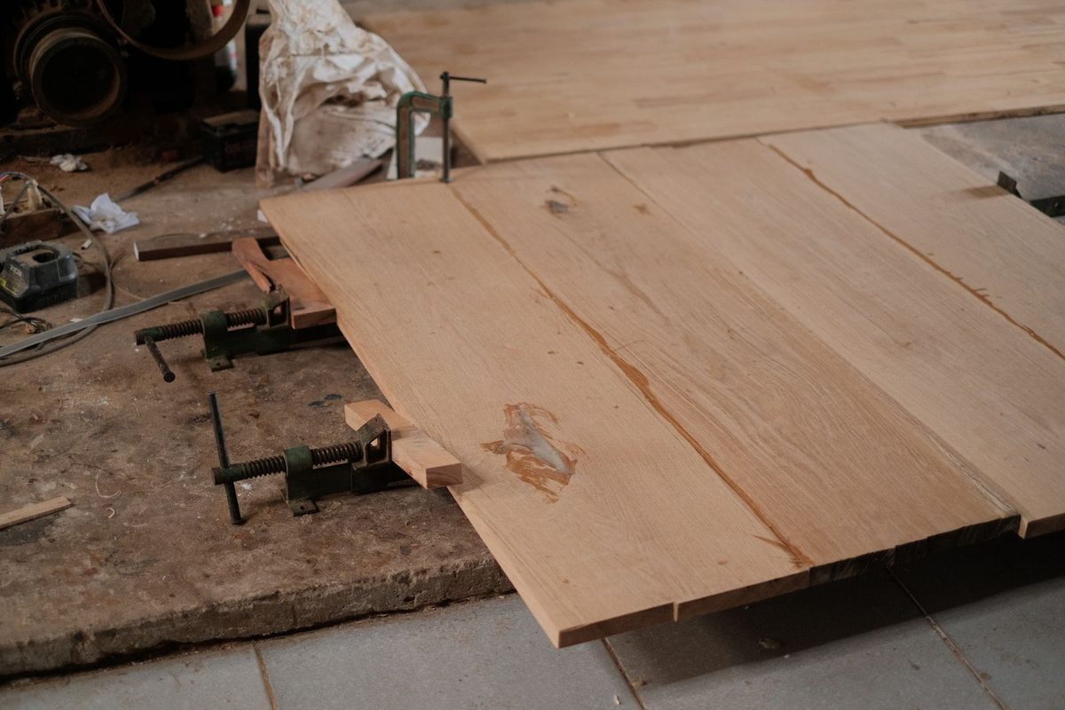 Oak boards clamped together on a workshop floor while the glue sets